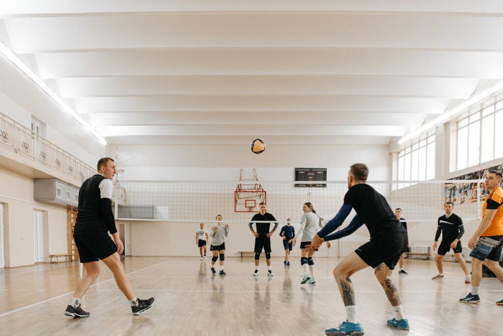 Players engaged in an exciting indoor volleyball game on a wooden floor court.