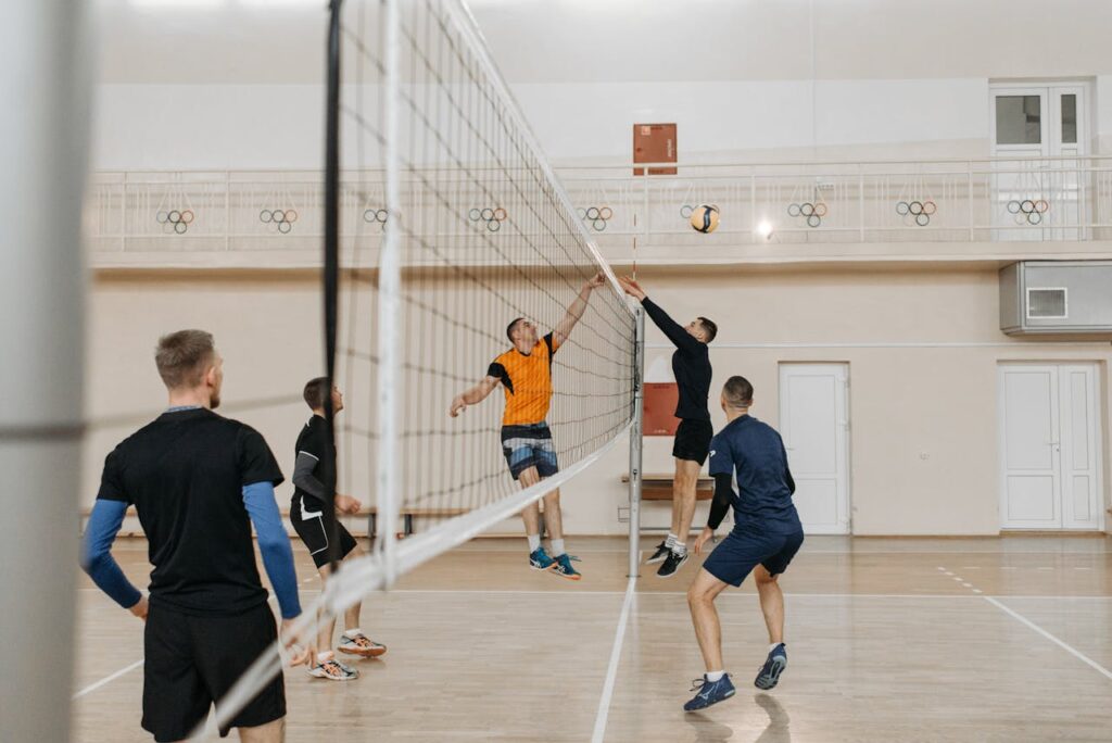 Exciting indoor volleyball match with athletes jumping to block and spike.