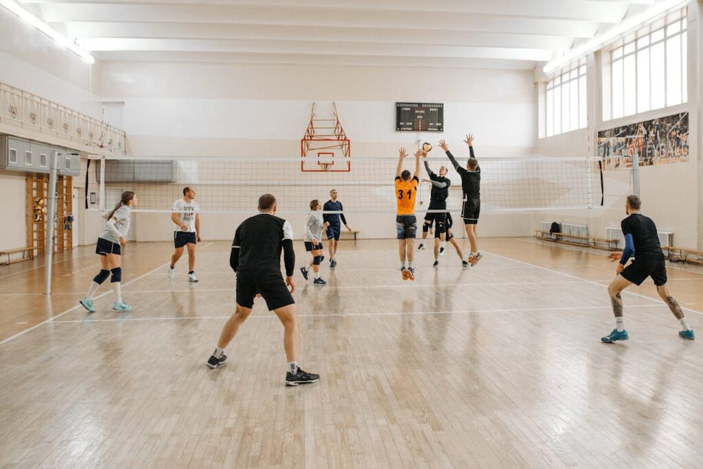 Action-packed volleyball game indoors with mixed-gender teams competing intensely.